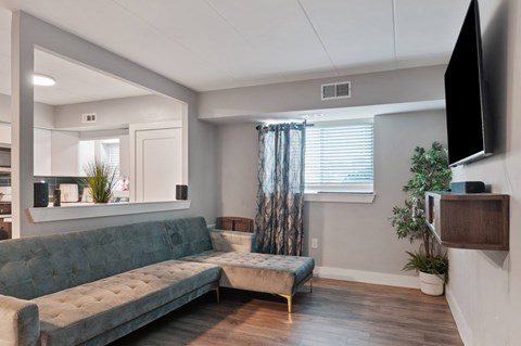 A living room with a grey couch and a television on the wall.