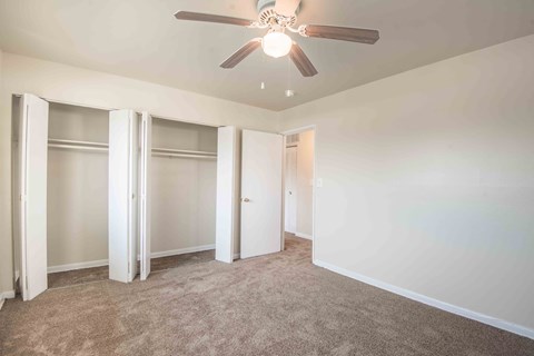 A room with a ceiling fan and carpeted floor.