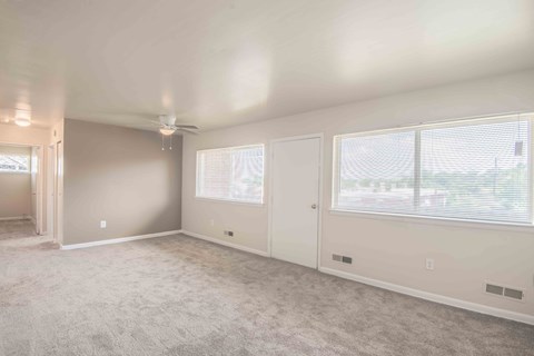 A spacious room with a carpeted floor and a ceiling fan.