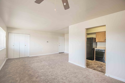 A room with a ceiling fan and a doorway leading to a kitchen.