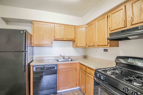 A kitchen with wooden cabinets and black appliances.