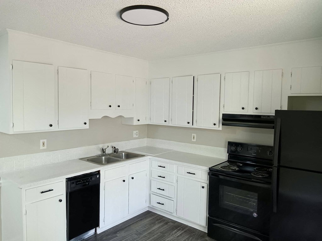 an empty kitchen with white cabinets and black appliances