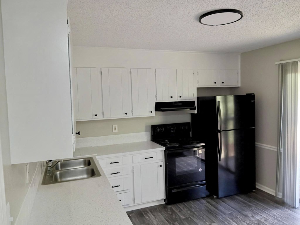 a kitchen with white cabinets and black appliances