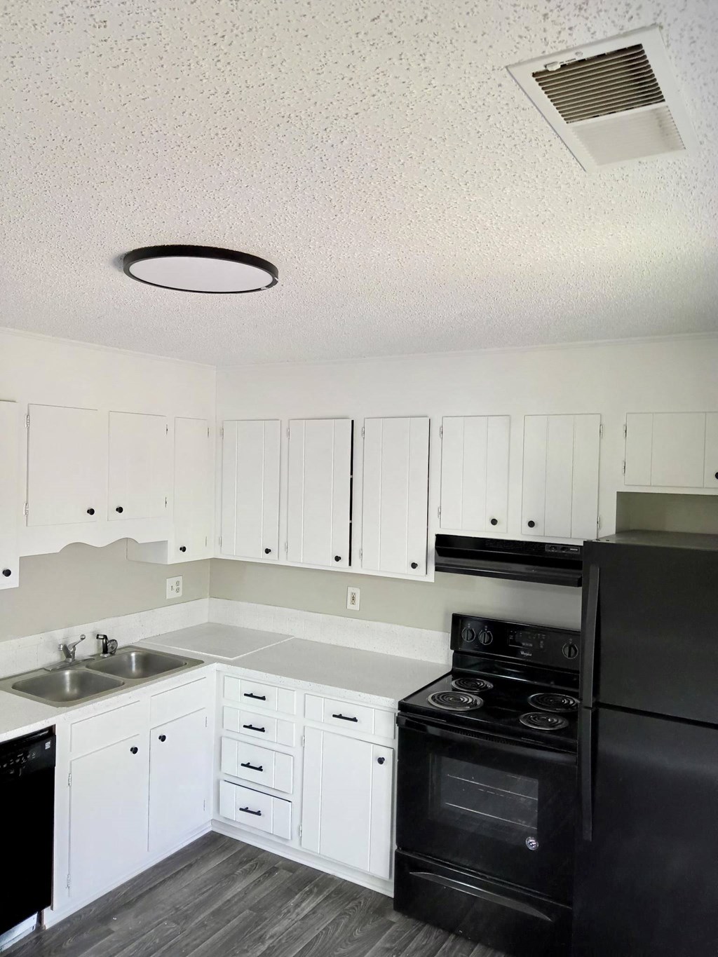 a kitchen with white cabinets and black appliances