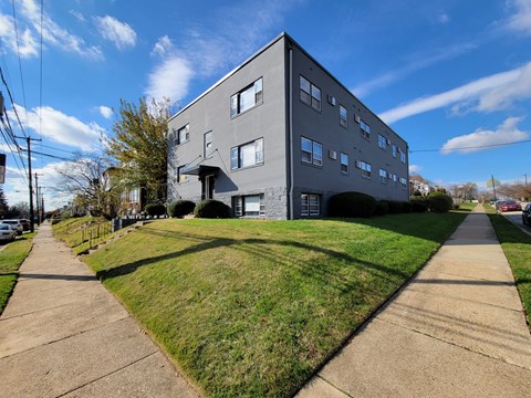 A grey building with a green lawn in front.