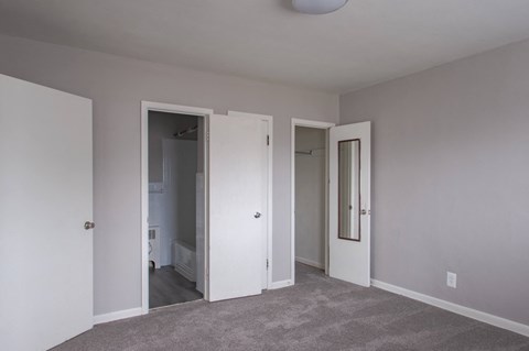 A room with a grey carpet and three doors.