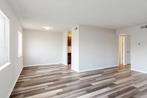 an empty living room with wood flooring and white walls