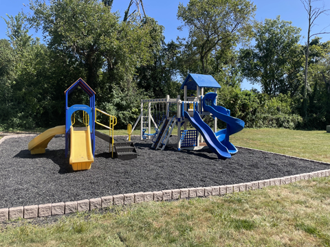 a playground with two slides and a swing set on a sunny day