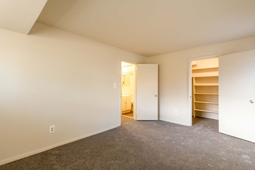 a bedroom with white walls and a closet with shelves