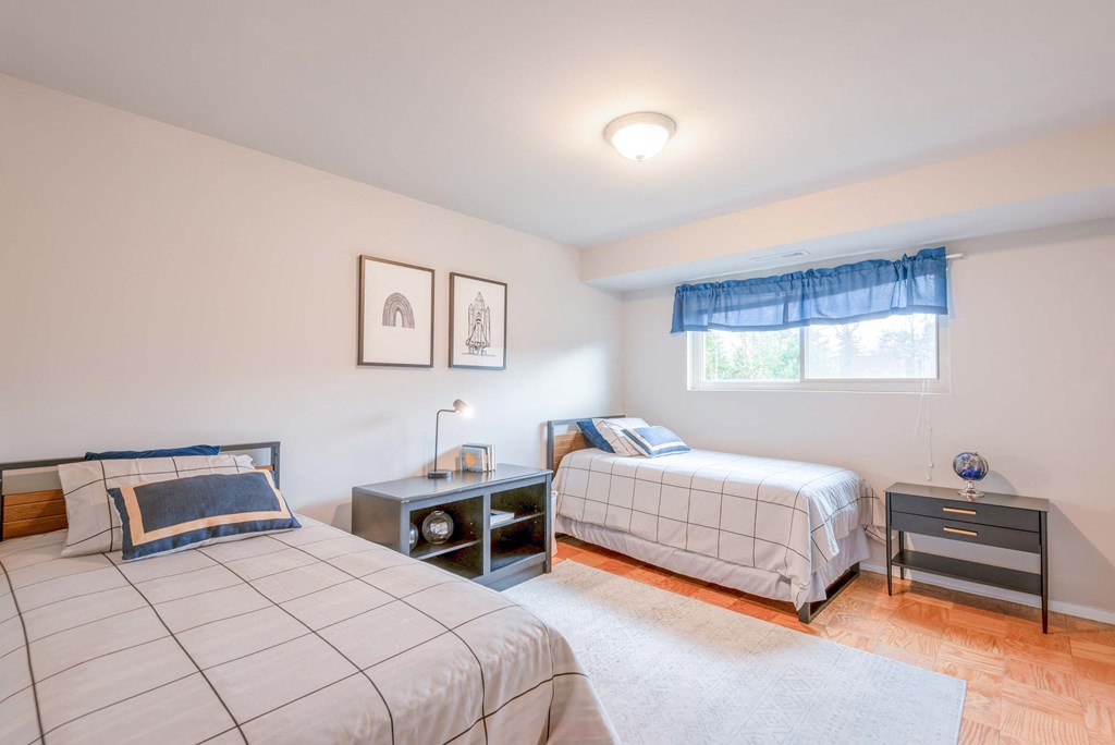 two twin beds in a bedroom with white walls and wood floors