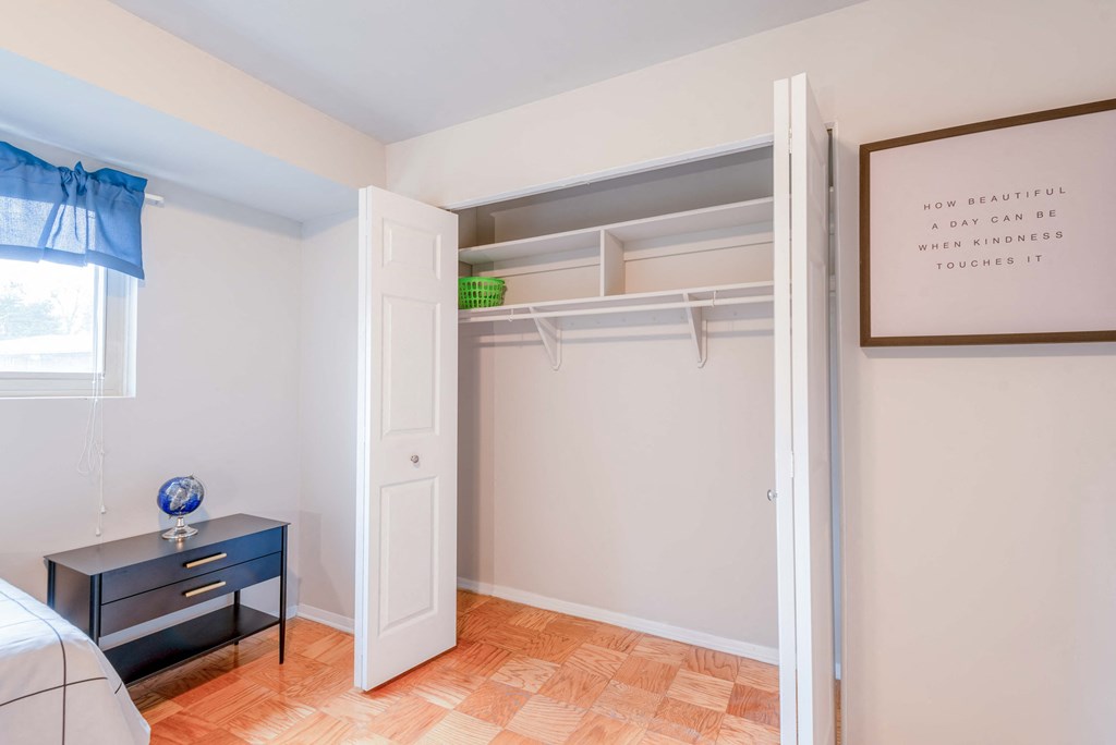 a closet in a bedroom with a bed and a dresser and a window