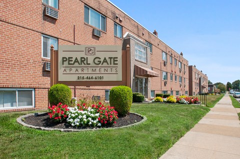 A brick building with a sign that says Pearl Gate Apartments.