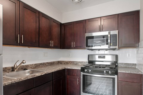 A kitchen with dark wood cabinets and a stainless steel oven.