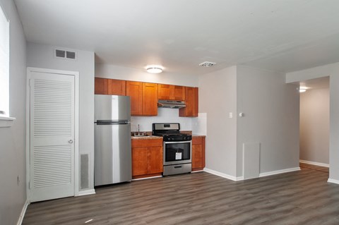 A kitchen with wooden cabinets and a stainless steel refrigerator.