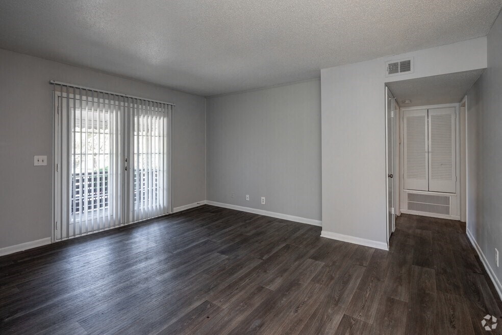 an empty living room with wood flooring and sliding glass doors