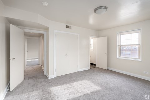 A spacious, empty room with white walls and carpeted floor.