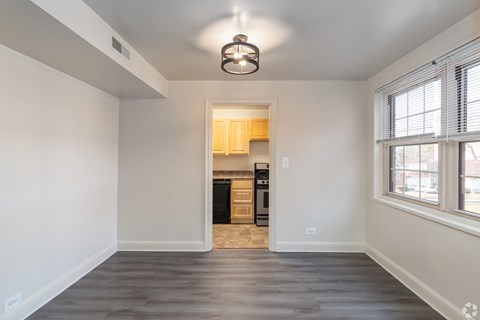 A spacious, empty room with a kitchen in the background.