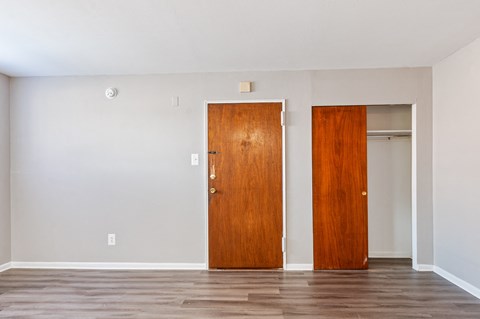 Two wooden doors in a room with a light grey wall.