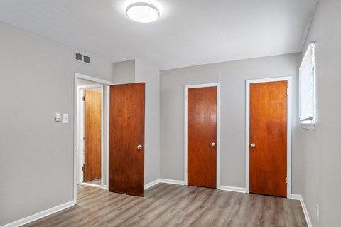 Three wooden doors in a room with light grey walls.