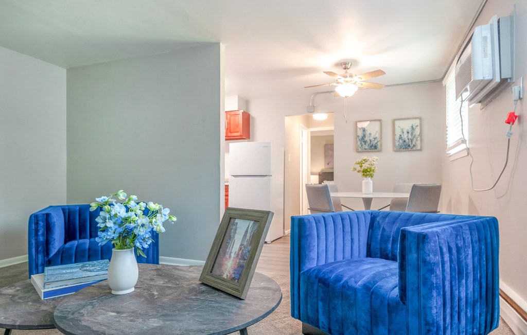 a living room with two blue couches and a coffee table with a vase of flowers