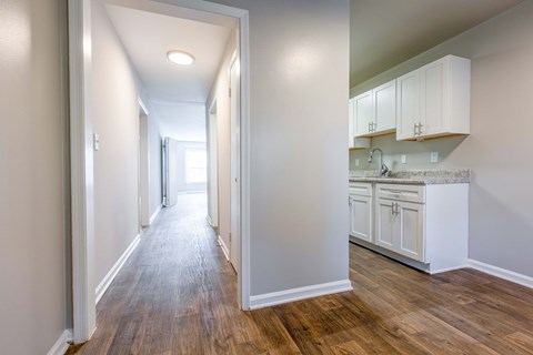 an empty kitchen with white cabinets and a wood floor
