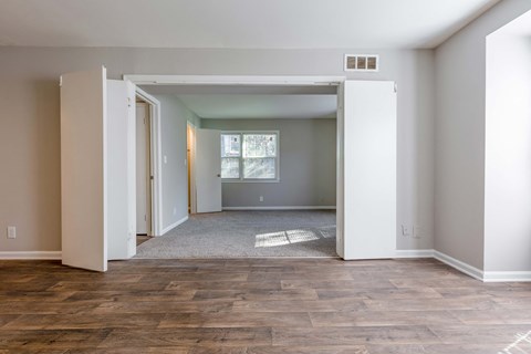 an empty living room with a door open to a bedroom