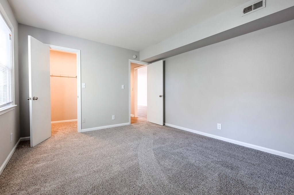 an empty living room with carpet and a door to a closet