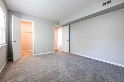 an empty living room with carpet and a door to a closet