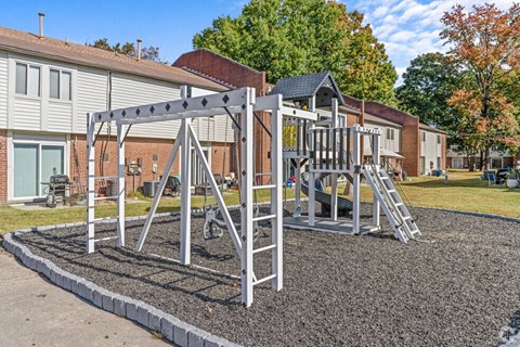A playground with a swing set and slide in front of a building.