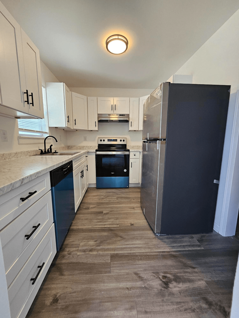 A kitchen with a black refrigerator and white cabinets.