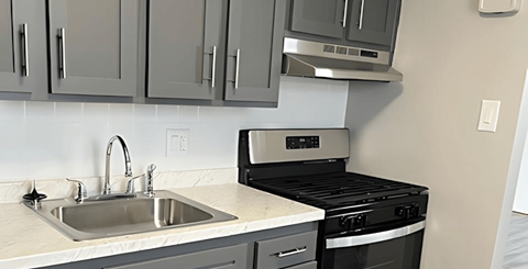 A kitchen with a sink, stove, and oven.