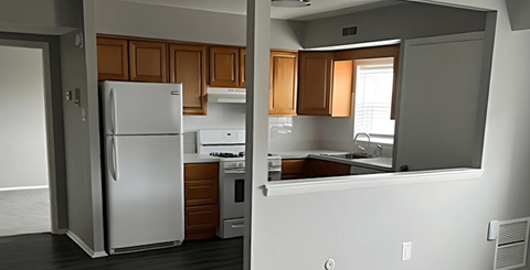 A kitchen with a white refrigerator and wooden cabinets.