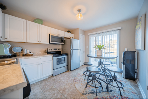 a kitchen with white cabinets and a table with four stools