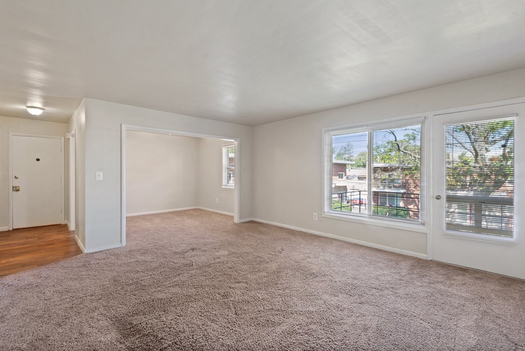 an empty living room with a large window and carpeting