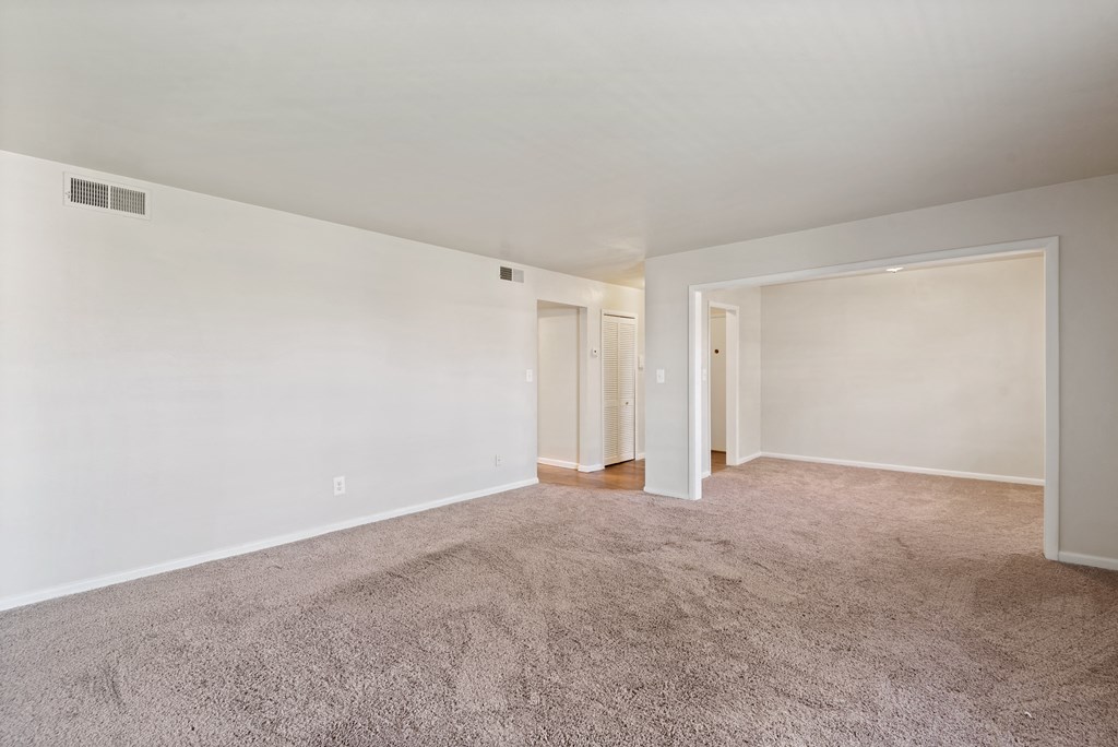 an empty living room with carpet and white walls