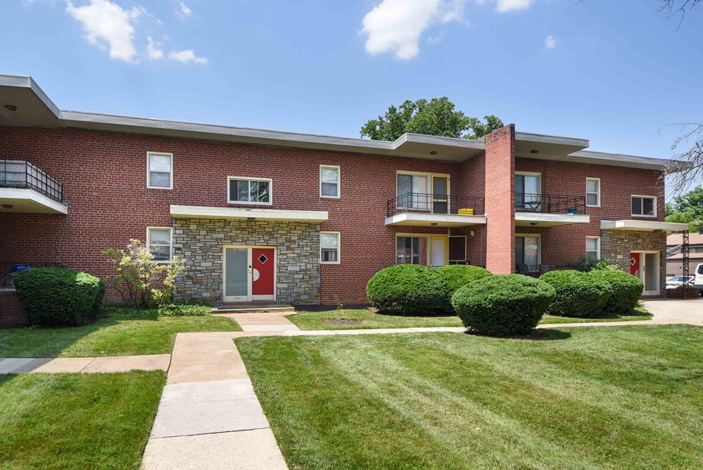 exterior view of a brick apartment building with a sidewalk and grass