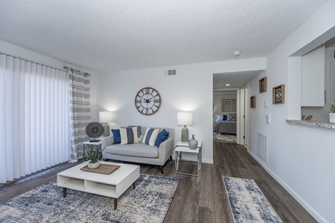A living room with a white couch and a clock on the wall.