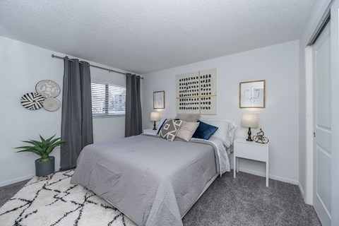 A bedroom with a bed, nightstand, and a wall hanging.