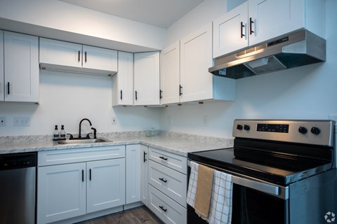 A kitchen with white cabinets and a black stove top oven.