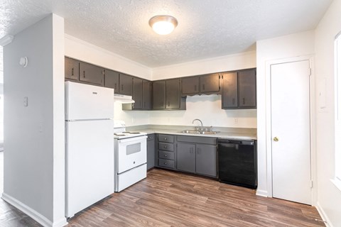 A kitchen with white appliances and wooden floors.