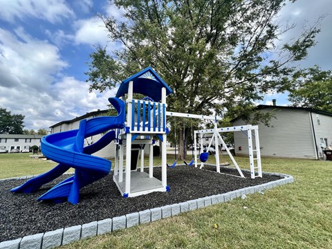A blue and white playground structure with a slide and swings.