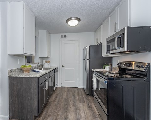 A kitchen with black appliances and white cabinets.