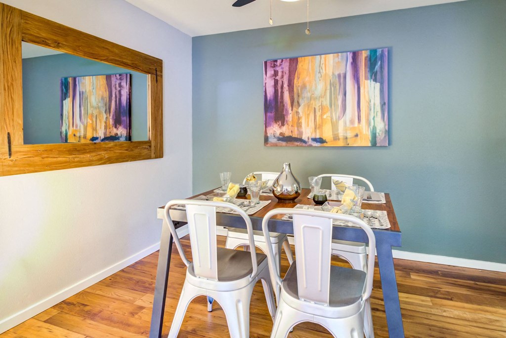 a dining room with a table and chairs and a painting on the wall