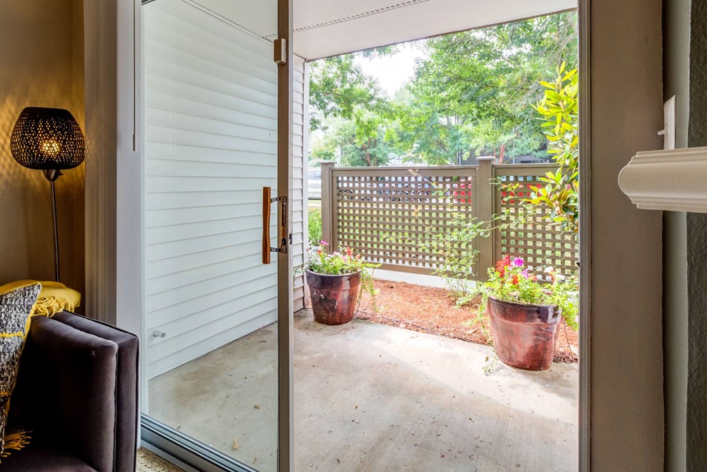 a sliding glass door opens to a patio with potted plants