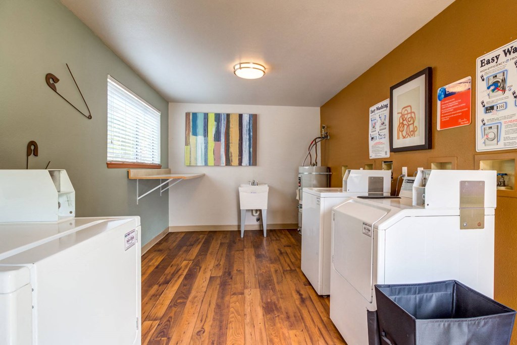 a laundry room with washes and dryers and a desk with a window and