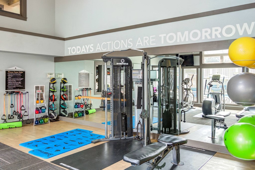 a gym with exercise equipment and a sign that says todays actions are tomorrow