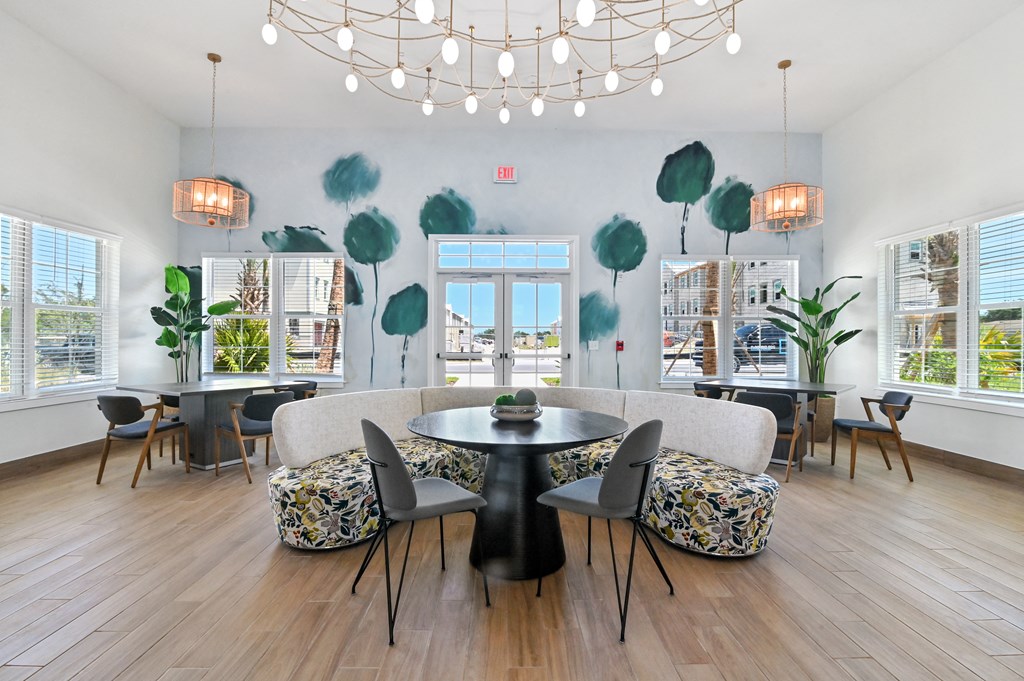 a living room with a table and chairs and green leaves on the walls