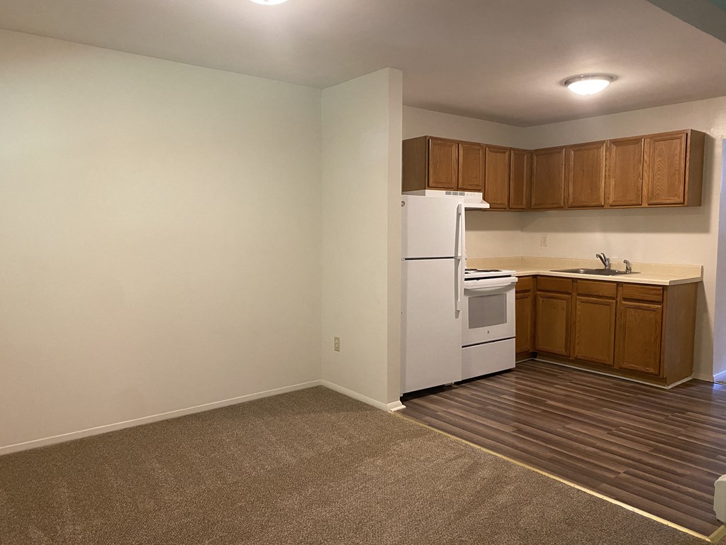 an empty kitchen with white appliances and wooden cabinets