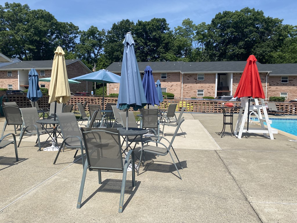 a poolside patio with tables and chairs and umbrellas
