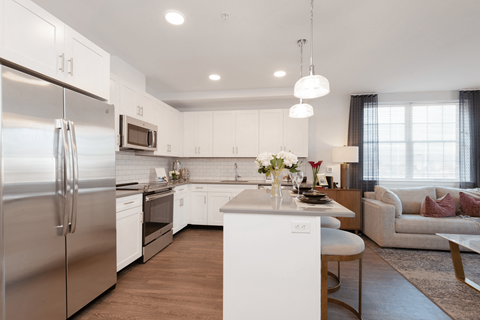 a kitchen and living room with stainless steel appliances and white cabinets